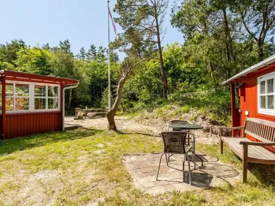 a picnic table and a bench in front of a cabin at Holiday Home Goodje - 400m from the sea by Interhome in Blokhus