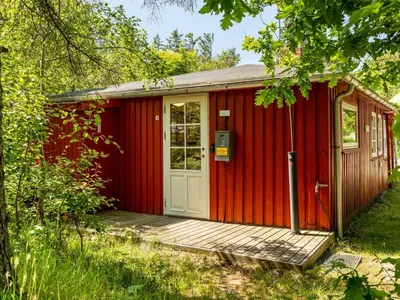 a red shed with a wooden porch and a door at Holiday Home Goodje - 400m from the sea by Interhome in Blokhus