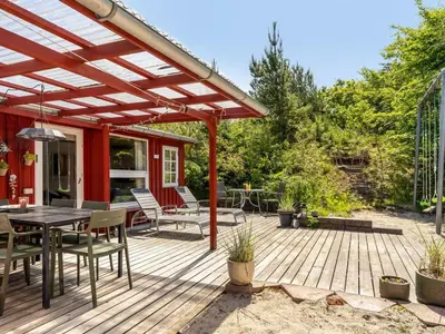a wooden deck with a table and chairs on it at Holiday Home Goodje - 400m from the sea by Interhome in Blokhus