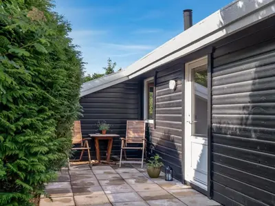 a patio with two chairs and a table next to a building at Holiday Home Laris - 700m to the fjord by Interhome in Løgsted