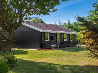 a black house with a porch and a yard at Holiday Home Laris - 700m to the fjord by Interhome in Løgsted