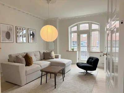 a living room with a white couch and a chair at Cozy pearl downtown Viborg in Viborg