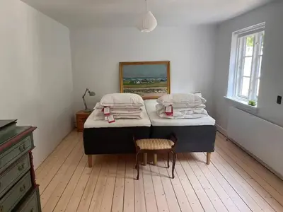 a bedroom with two twin beds and a chair at Villa Bakkely in Lemvig