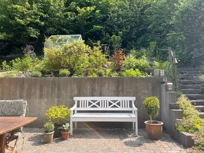 a white bench sitting in front of a concrete wall at Villa Bakkely in Lemvig