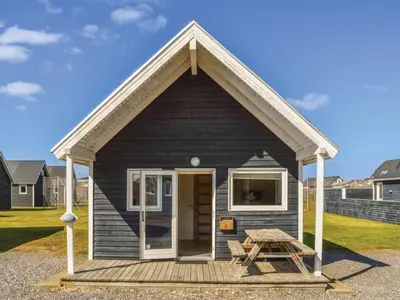 a small black house with a picnic table in front of it at 4 star holiday home in Thyborøn in Thyborøn