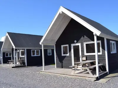 a black and white house with a picnic table in front at 4 star holiday home in Thyborøn in Thyborøn