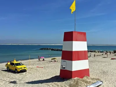 a yellow car parked next to a red and white lighthouse on a beach at 4 star holiday home in Thyborøn in Thyborøn