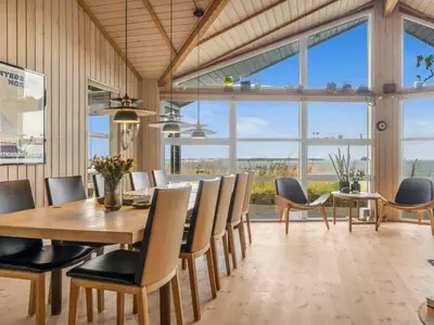 a dining room with a table and chairs and large windows at Holiday Home Diderik - 20m to the fjord by Interhome in Roslev
