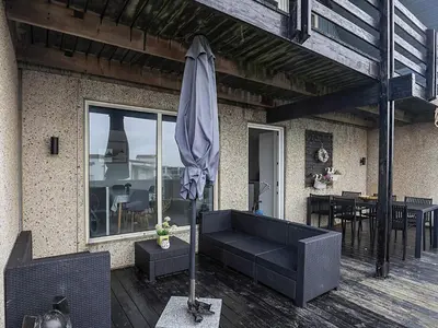a patio with a black couch and an umbrella at 6 person holiday home in Vestervig in Vestervig