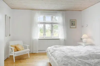 a bedroom with a bed and a chair and a window at 872-Bedsted-Thy-Lyngbyvej-25 in Bedsted Thy