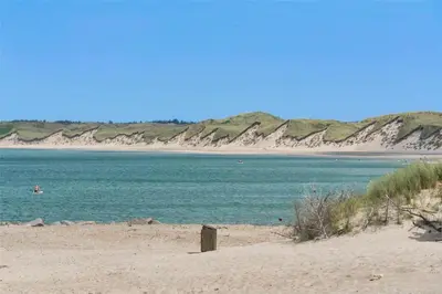 a beach with a person in the water and mountains at 465-Thisted-Havbovej-25 in Thisted
