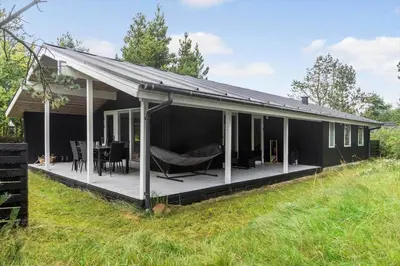 a black house with a porch with a hammock on it at 891-Snedsted-Grahavrevej-21 in Snedsted