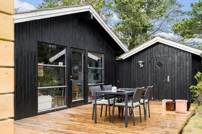 a black house with a table and chairs on a deck at 1014-Thisted-Sletningen-7 in Torsted