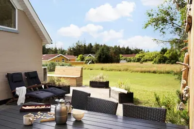 a patio with a table and chairs and a field at 492-Thisted-Tunvej-7-B in Thisted