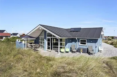 a blue house on the beach with chairs at 898-Thisted-Nordsovej-46-B in Thisted