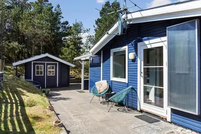 a blue house with two chairs on a patio at 257-Thisted-Blamunkevej-34 in Thisted