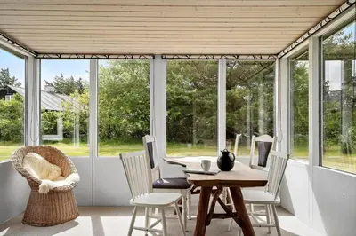 a dining room with a table and chairs and windows at 140-Vestervig-Bekkasinvej-14 in Vestervig