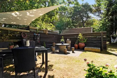 a patio with tables and chairs and an umbrella at 216-Snedsted-Grahavrevej-6 in Snedsted