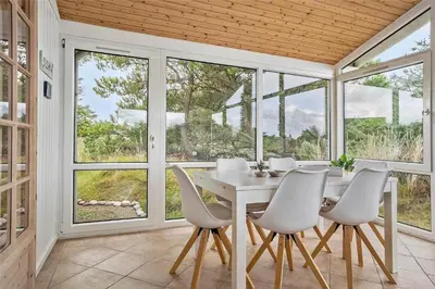 a dining room with a table and chairs and windows at 767-Thisted-Nordsovej-63 in Thisted
