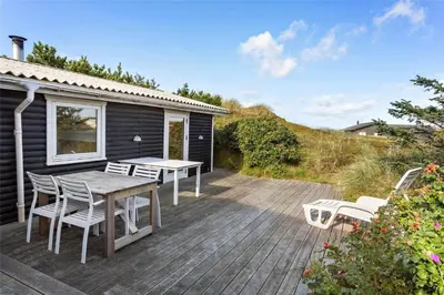 a wooden deck with a table and chairs on it at 996-Thisted-Bavnbak-25 in Torsted