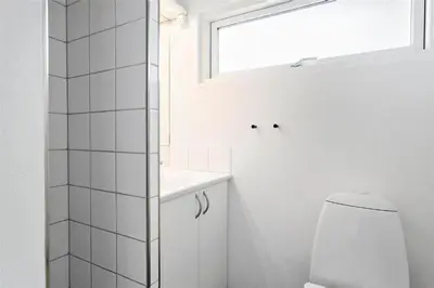 a white bathroom with a toilet and a window at 996-Thisted-Bavnbak-25 in Torsted