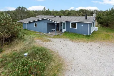 a blue house in a field next to a dirt road at 849-Thisted-Havtornvej-6 in Thisted