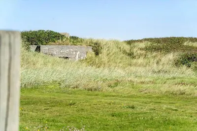 a grassy field with an old building on the side of a hill at 306-Vestervig-Klitvej-6 in Vestervig