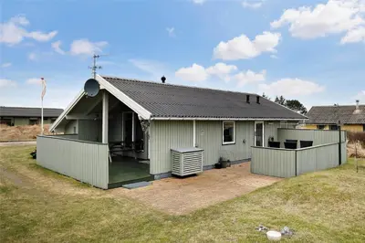 a small green house with a patio in a yard at 802-Thisted-Pighvarvej-22 in Thisted