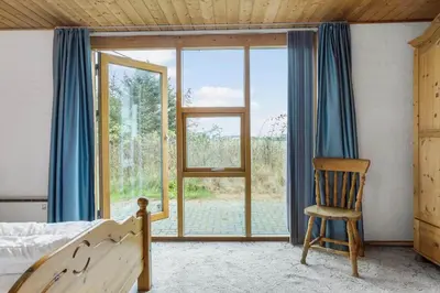 a bedroom with a bed and a chair and a window at 648-Thisted-Kuttervej-8 in Thisted