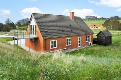 a small red house with a balcony on top of a field at 161-Hanstholm-Kraegpotvej-161 in Hanstholm