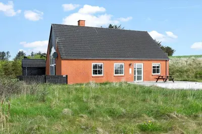 a red house with a bench in front of it at 161-Hanstholm-Kraegpotvej-161 in Hanstholm