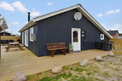 a black house with a wooden deck with a bench at 867-Thisted-Nordsovej-66 in Thisted