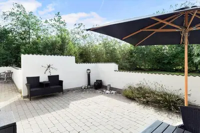 a patio with a black chair and an umbrella at 496-Snedsted-Niels-Juels-Vej-33 in Snedsted