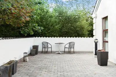 a patio with two chairs and a table against a white wall at 496-Snedsted-Niels-Juels-Vej-33 in Snedsted