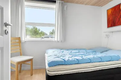 a bedroom with a bed and a chair and a window at 618-Thisted-Fiskervej-82 in Thisted