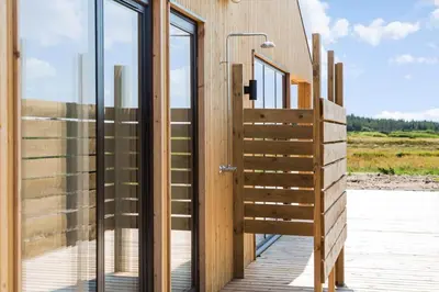 a wooden house with glass doors and a wooden deck at 1056-Thisted-Johns-Vej-16 in Torsted