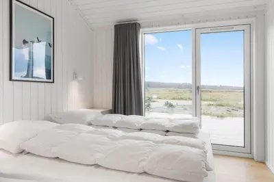 a white bedroom with two beds and a large window at 1056-Thisted-Johns-Vej-16 in Torsted