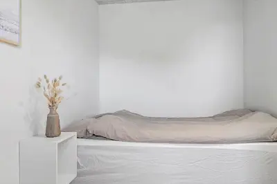 a white bedroom with a bed and a vase on a night stand at 1302-Thisted-Havstokken-30-1 in Thisted