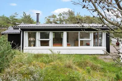 a small house with white windows on a field at 645-Thisted-Blabaervej-4 in Thisted