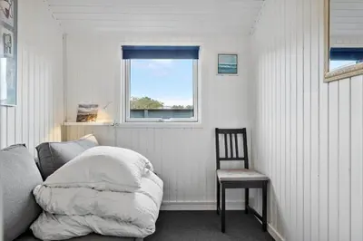 a bedroom with a chair and a pillow and a window at 1059-Klitmoller-Mollebakken-56 in Klitmøller