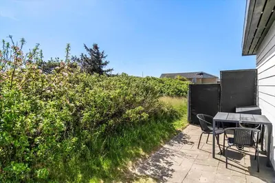 a patio with a table and chairs next to a hedge at 586-Thisted-Havbovej-30 in Thisted