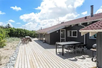 a wooden deck with a table and chairs on a house at 975-Thisted-Klitstien-45 in Torsted