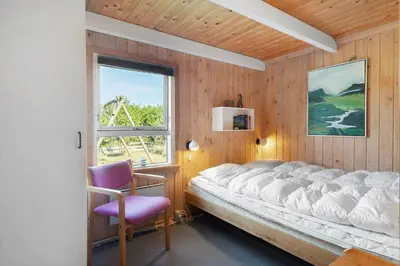 a bedroom with a bed and a chair and a window at 675-Thisted-Tunvej-15 in Thisted