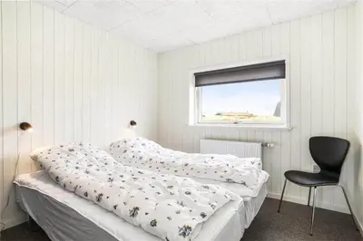 a bedroom with a bed and a chair and a window at 899-Snedsted-Somaerkevej-76-B in Snedsted