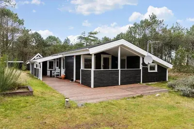 a black house with a wooden deck in a field at 873-Thisted-Blamunkevej-67 in Thisted