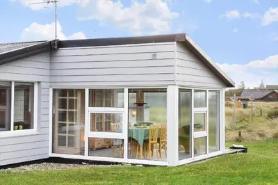 a white house with sliding glass doors and a table at 276-Thisted-Nordsovej-76 in Thisted