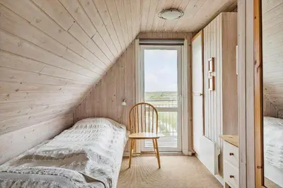 a bedroom with a bed and a chair and a window at 186-Vestervig-Magevej-5 in Vestervig
