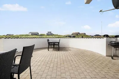 a patio with two chairs and a table and a grill at 186-Vestervig-Magevej-5 in Vestervig