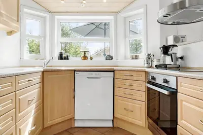a kitchen with wooden cabinets and a white dishwasher at 1050-Thisted-Spanggardsvej-5 in Torsted