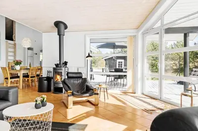 a living room with a fireplace and a table with chairs at 1050-Thisted-Spanggardsvej-5 in Torsted